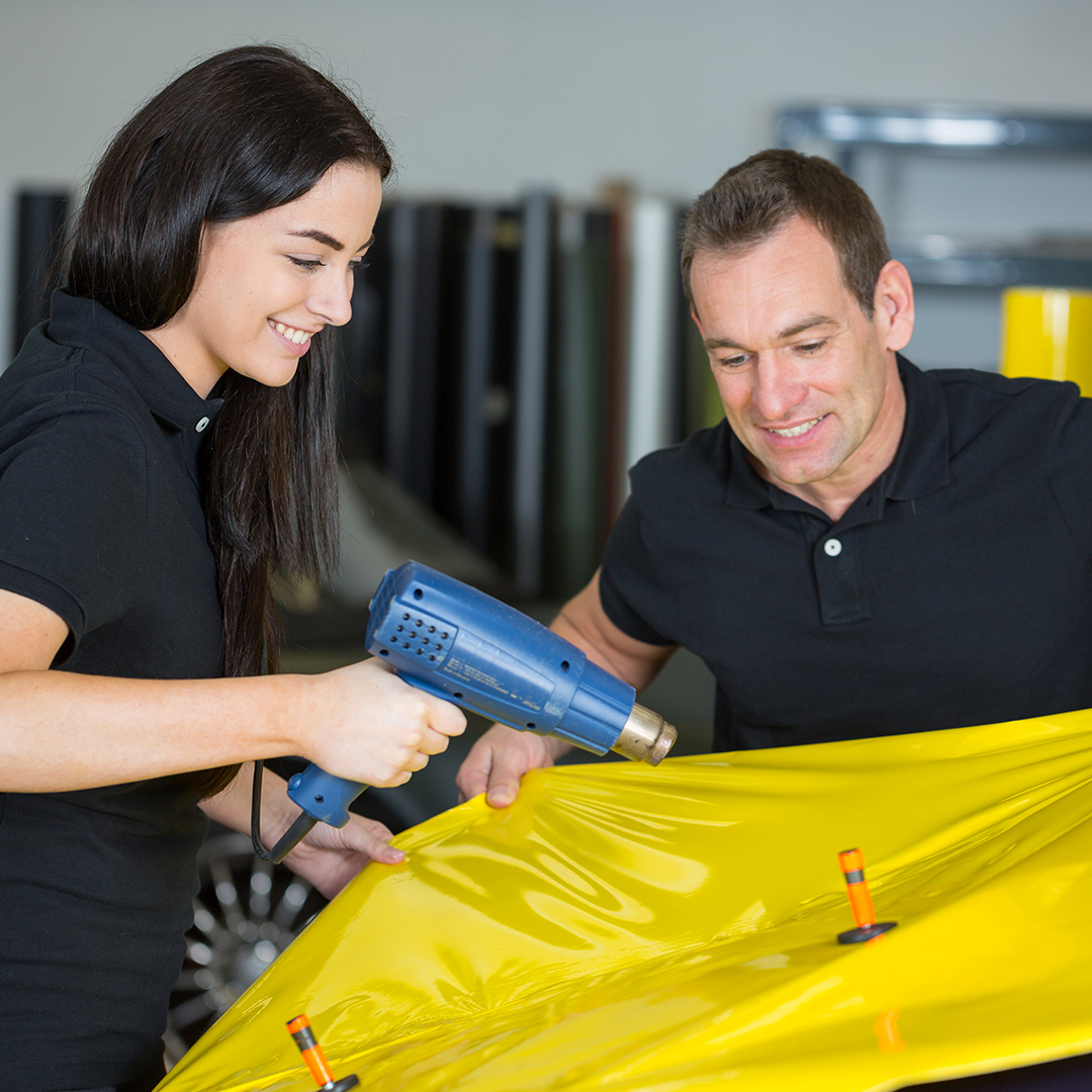 Image of a man and woman applying a car wrap